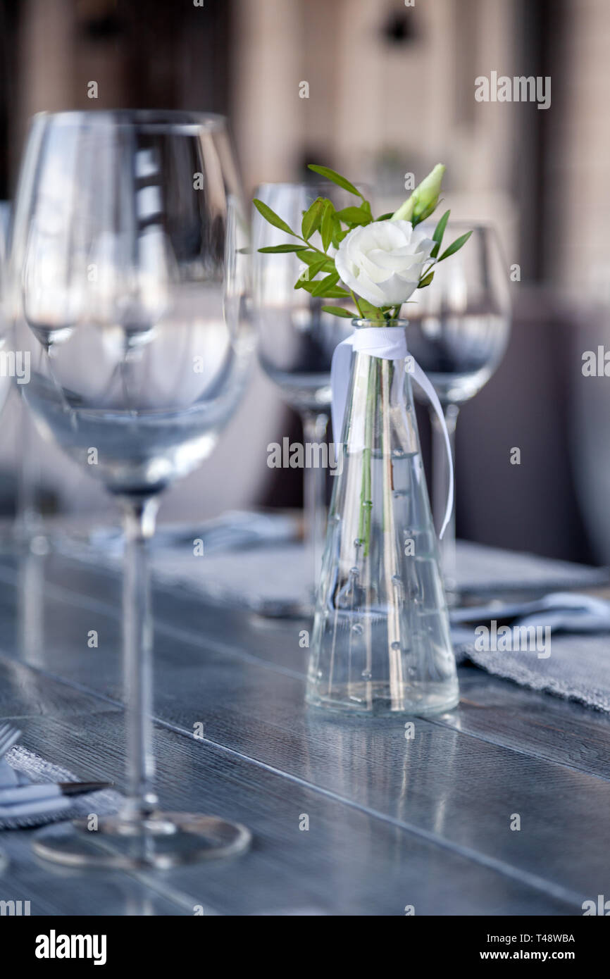 Vase en verre transparent avec bouquet de fleurs contre l'arrière-plan de  la table, dans un restaurant moderne. Vin et verres à eau stand dans la  rangée de maisons Photo Stock - Alamy