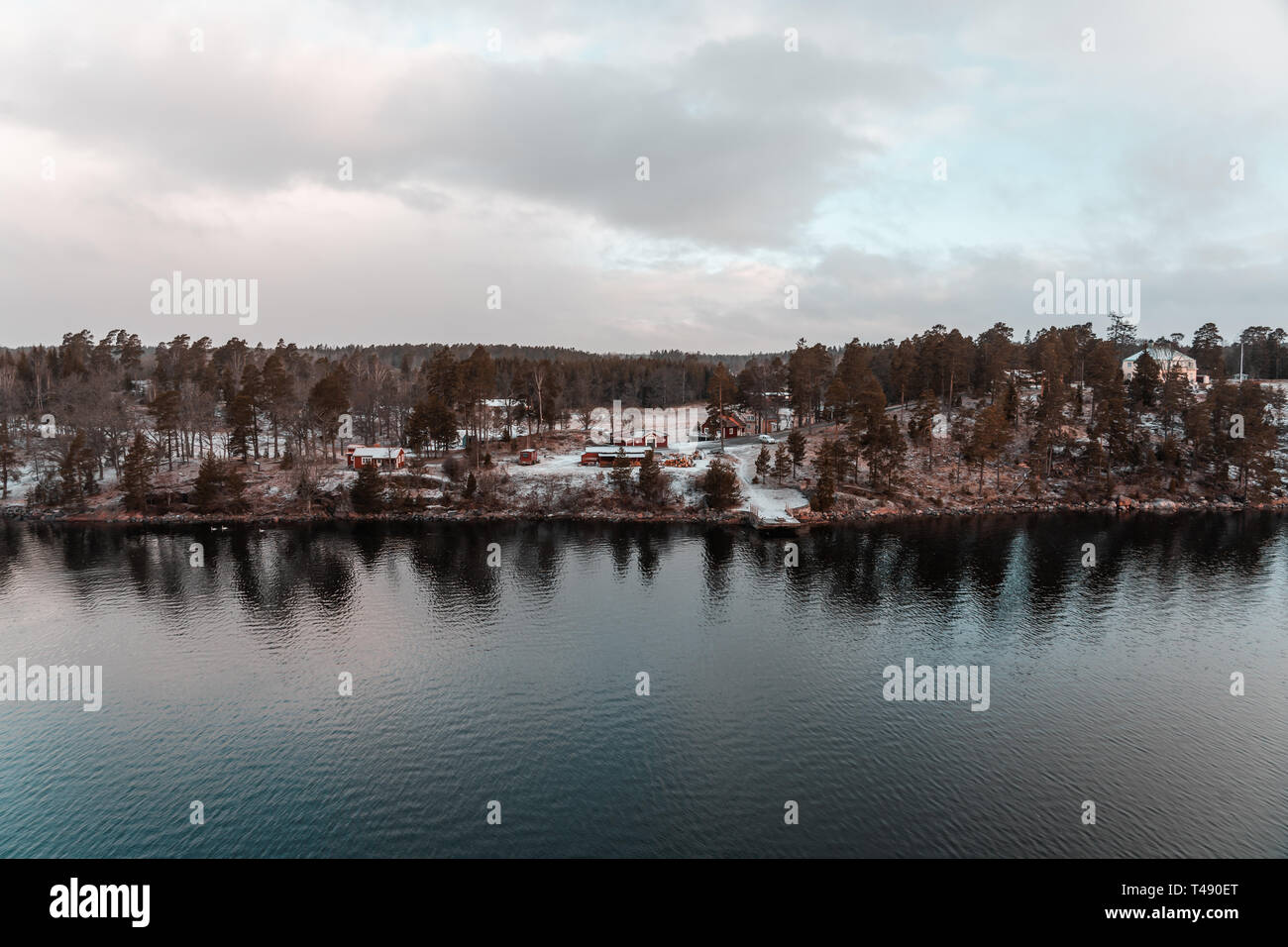 Vue de l'archipel de Stockholm avec neige au sol avec des maisons dans les bois et l'eau qui reflète, en Suède Banque D'Images