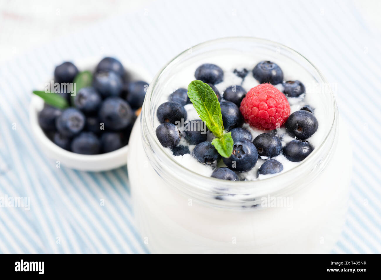 Yaourt avec blueberies en pot, vue rapprochée. Riche en calcium et en protéines de yaourt grec surmontée de bleuets frais, de framboise et de feuille de menthe Banque D'Images