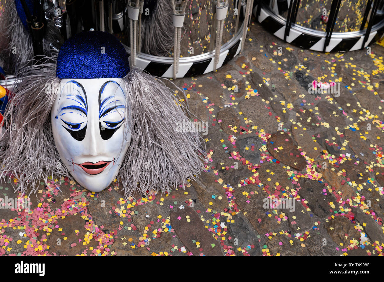 Augustinergasse, Bâle, Suisse - Mars 12th, 2019. Close-up d'un masque de carnaval et caisse claire sur une rue couverte de confettis Banque D'Images