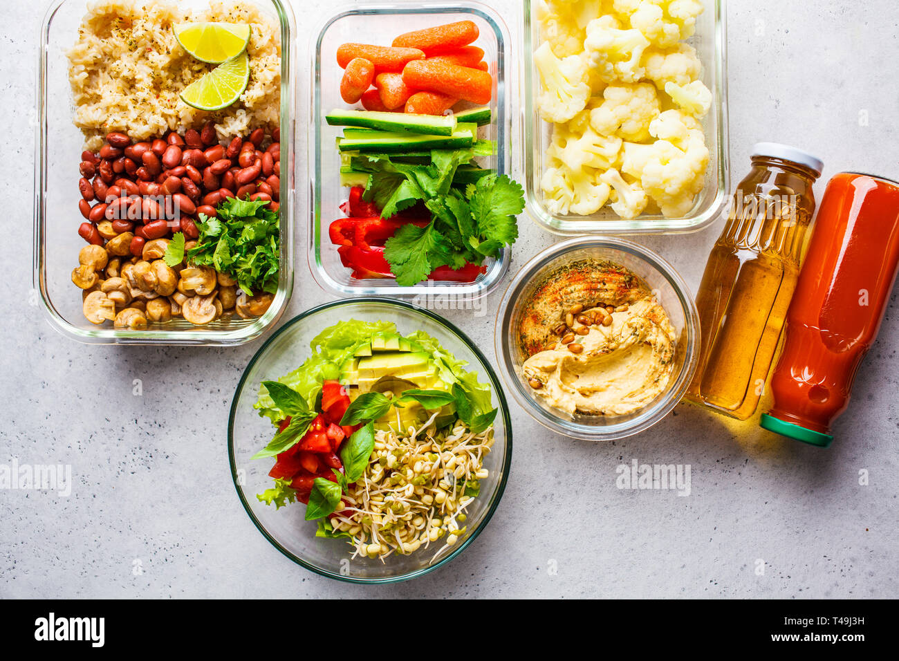 La nourriture végétalienne saine dans des récipients en verre, vue d'en haut. Riz, haricots, légumes, hoummos et jus pour le déjeuner à emporter Banque D'Images