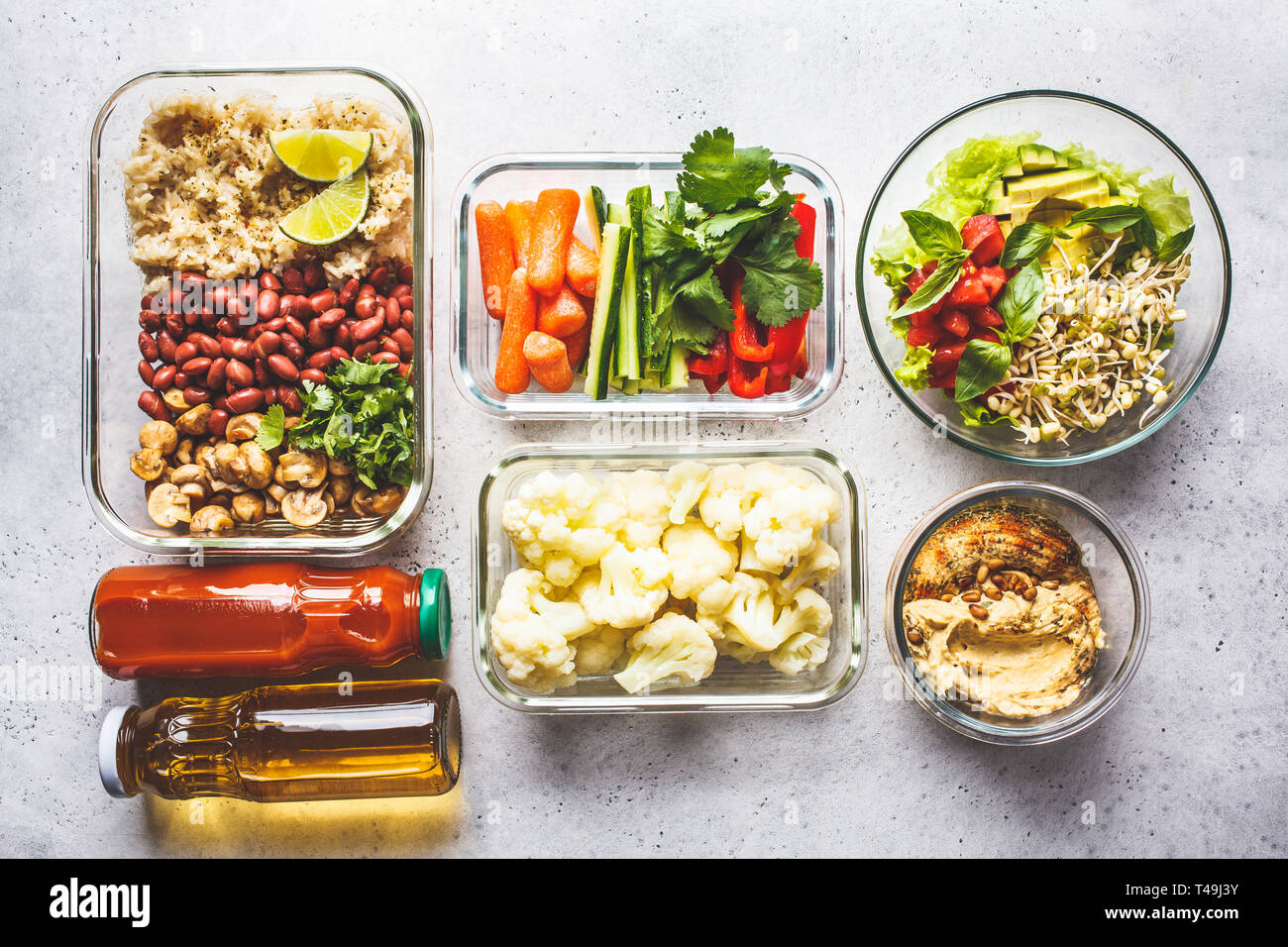 La nourriture végétalienne saine dans des récipients en verre, vue d'en haut. Riz, haricots, légumes, hoummos et jus pour le déjeuner à emporter Banque D'Images