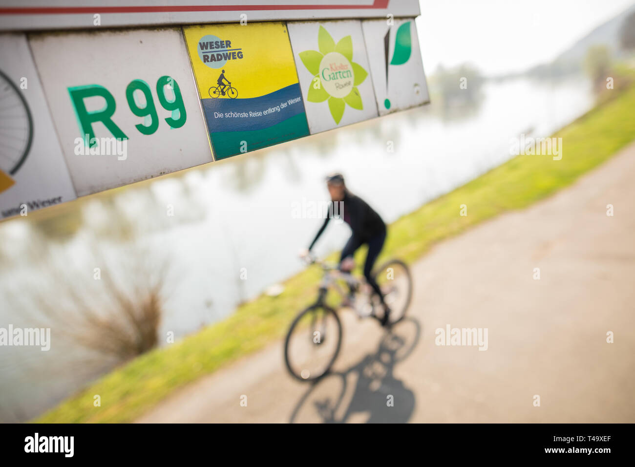 06 avril 2019, en Rhénanie du Nord-Westphalie, Hagen : disques durs un cycliste le long de la piste cyclable Weser passé une indication, dans laquelle, entre autres choses, un panneau avec l'inscription 'Weser cycle path - le plus beau voyage le long de la Weser' est joint. Les 520 kilomètres à vélo longue distance, qui est la plus populaire en Allemagne selon l'ADFC 2019 Travelbike l'analyse, s'étend le long de la Weser à travers les états fédéraux de Brême, Hesse, Basse-Saxe et de Rhénanie du Nord-Westphalie. Photo : Moritz Frankenberg/dpa Banque D'Images