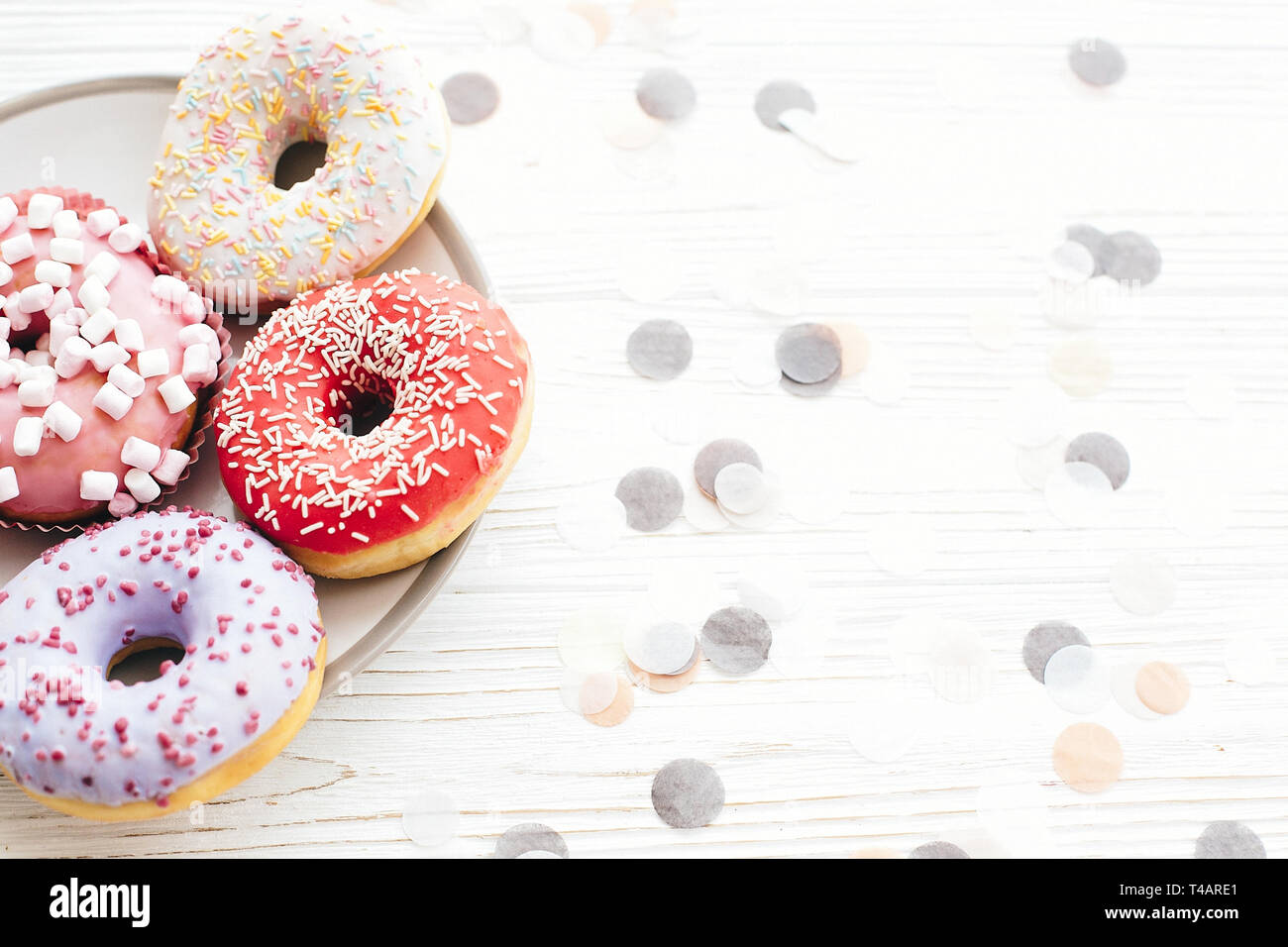 Délicieux donuts colorés avec sprinkles et guimauves à la plaque sur le tableau blanc élégant de confettis. Partie concept. Pas de régime alimentaire. Candy bar at wedding Banque D'Images