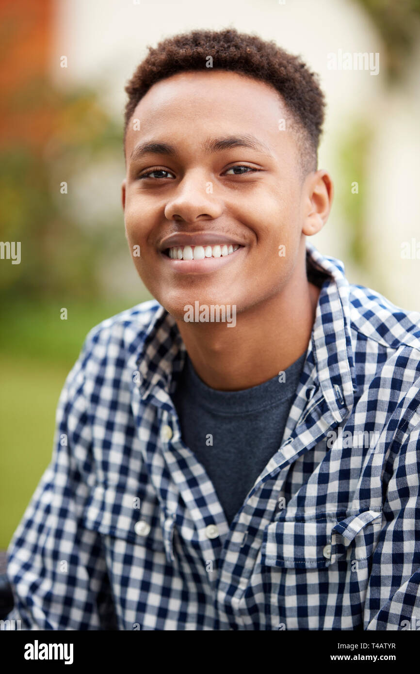 Jeune homme noir à l'extérieur des sourires à l'appareil photo, Close up, vertical Banque D'Images