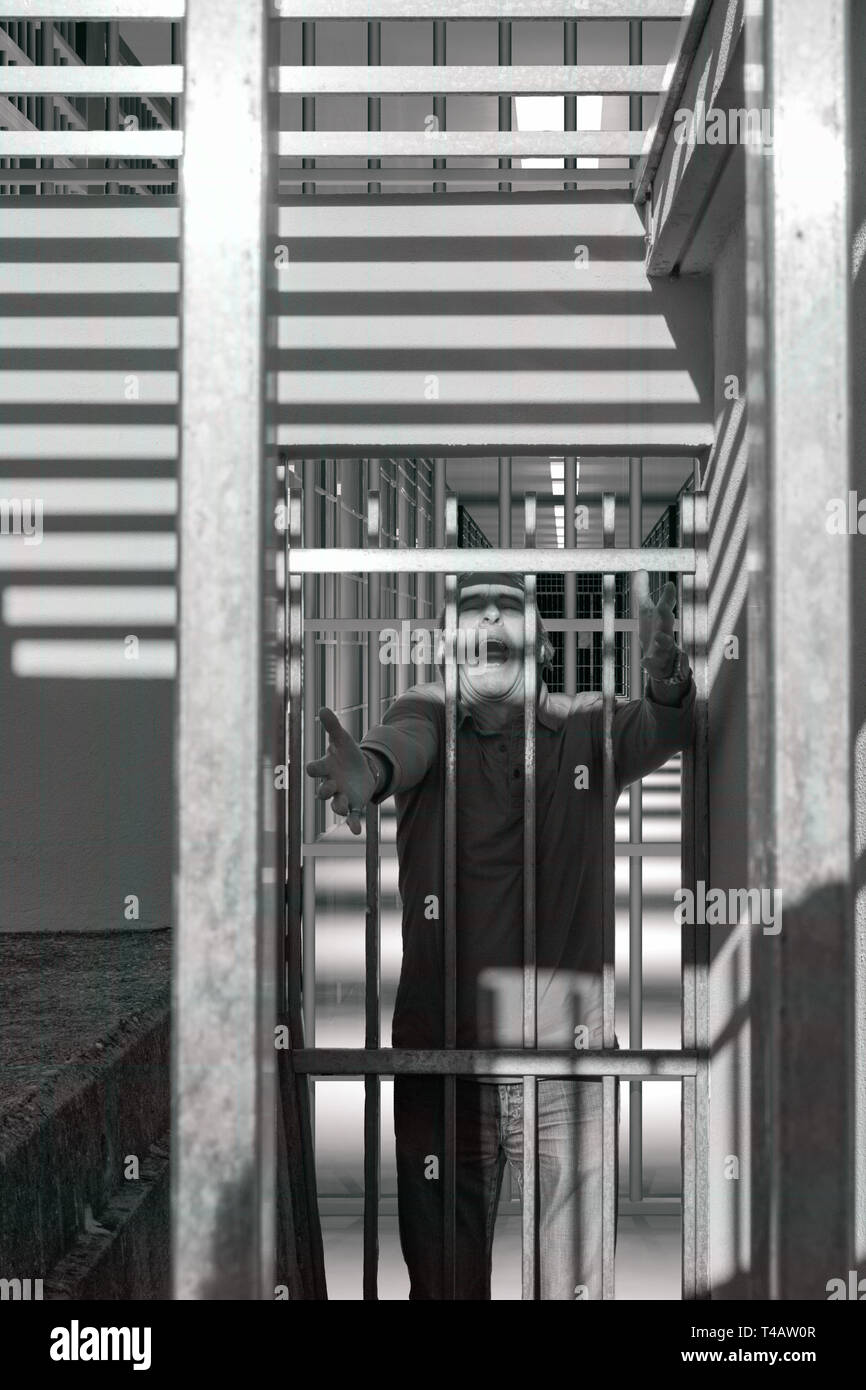 A condamné l'homme derrière les barreaux d'une porte de prison, des cris de peur et de colère Banque D'Images