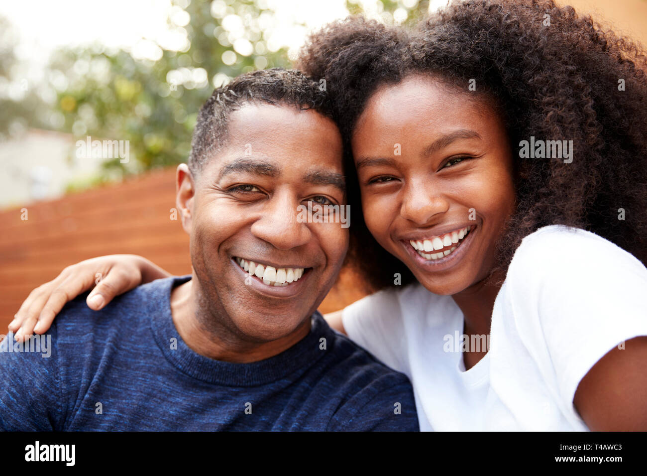 Noir d'âge moyen père et fille adolescente embrassant et souriant à la caméra, Close up Banque D'Images