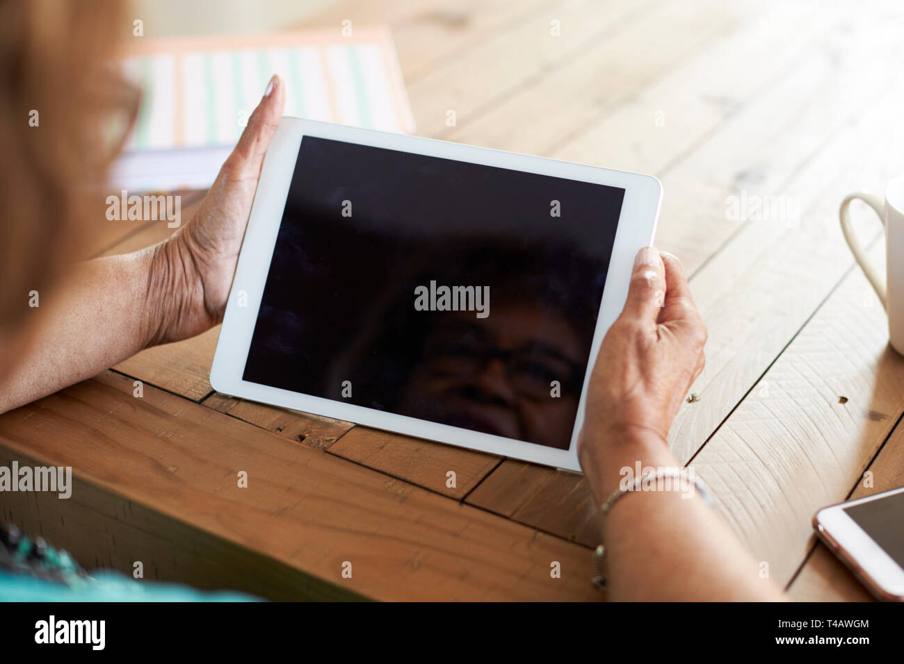 Plus d'épaule d'un senior woman's hands holding a tablet computer, selective focus Banque D'Images