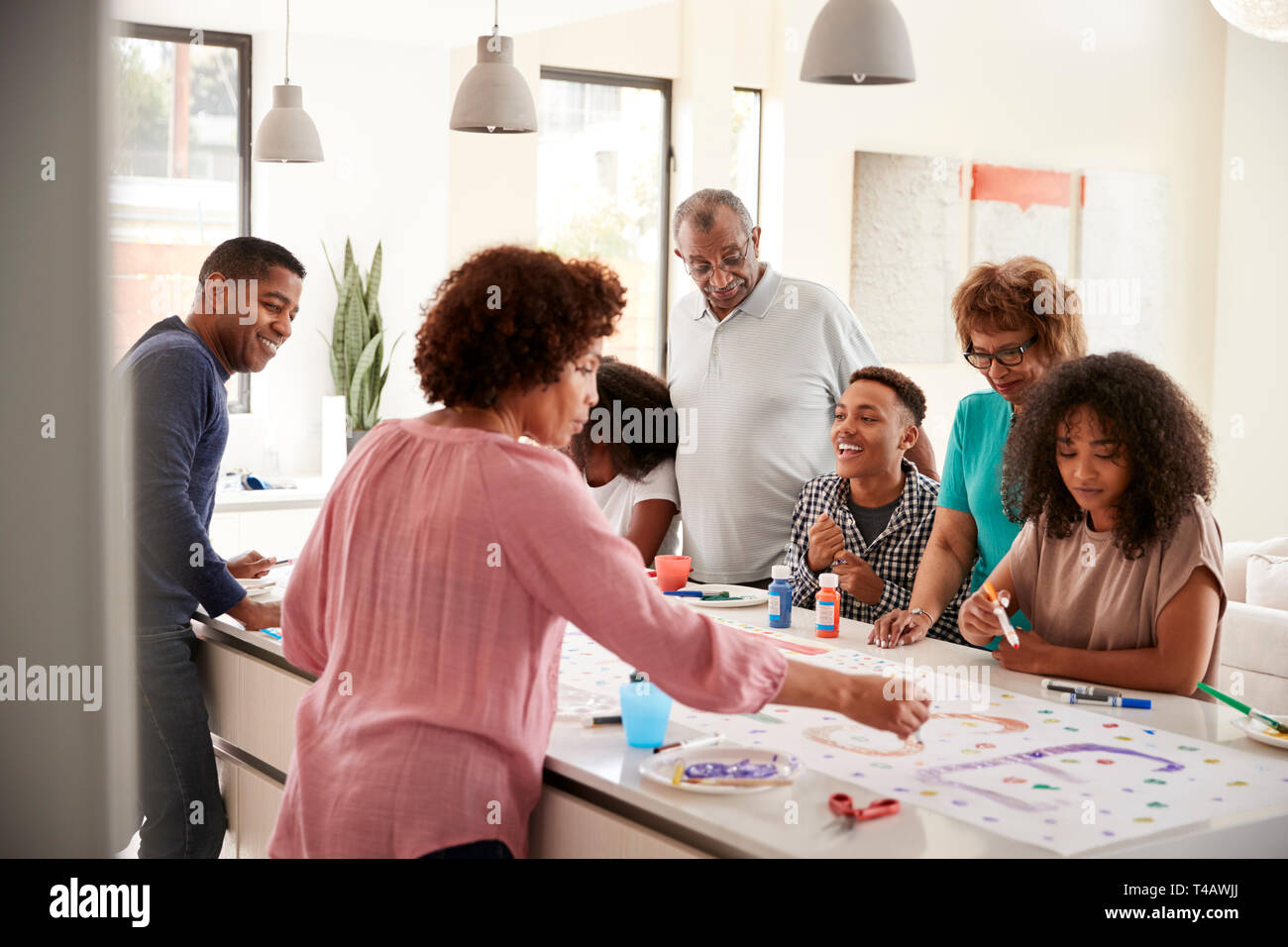 Trois générations de la famille noire préparer une enseigne pour une fête surprise dans leur cuisine, Close up Banque D'Images