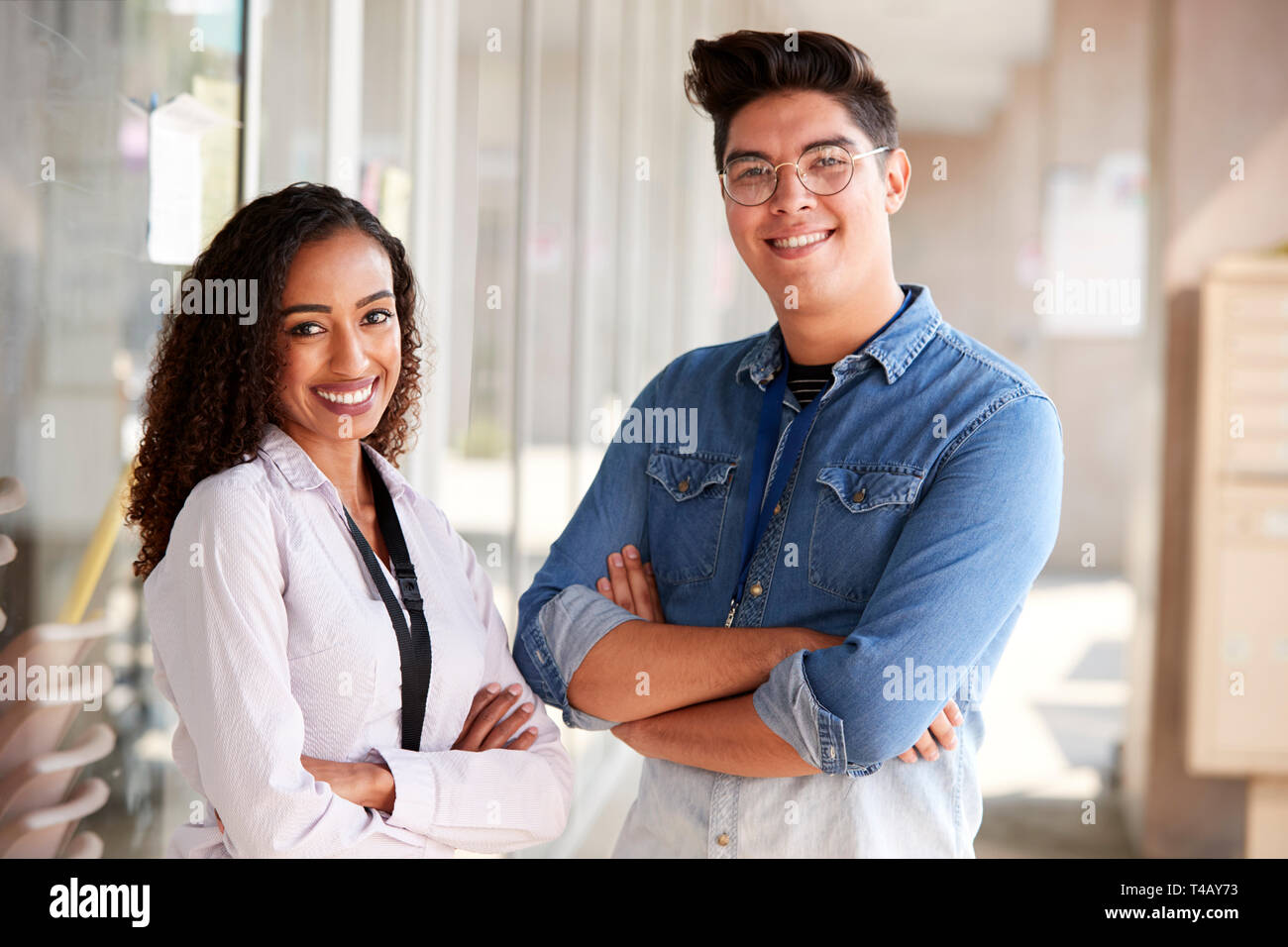 Portrait Of Smiling male et femelle School Teachers debout dans Couloir de College Building Banque D'Images