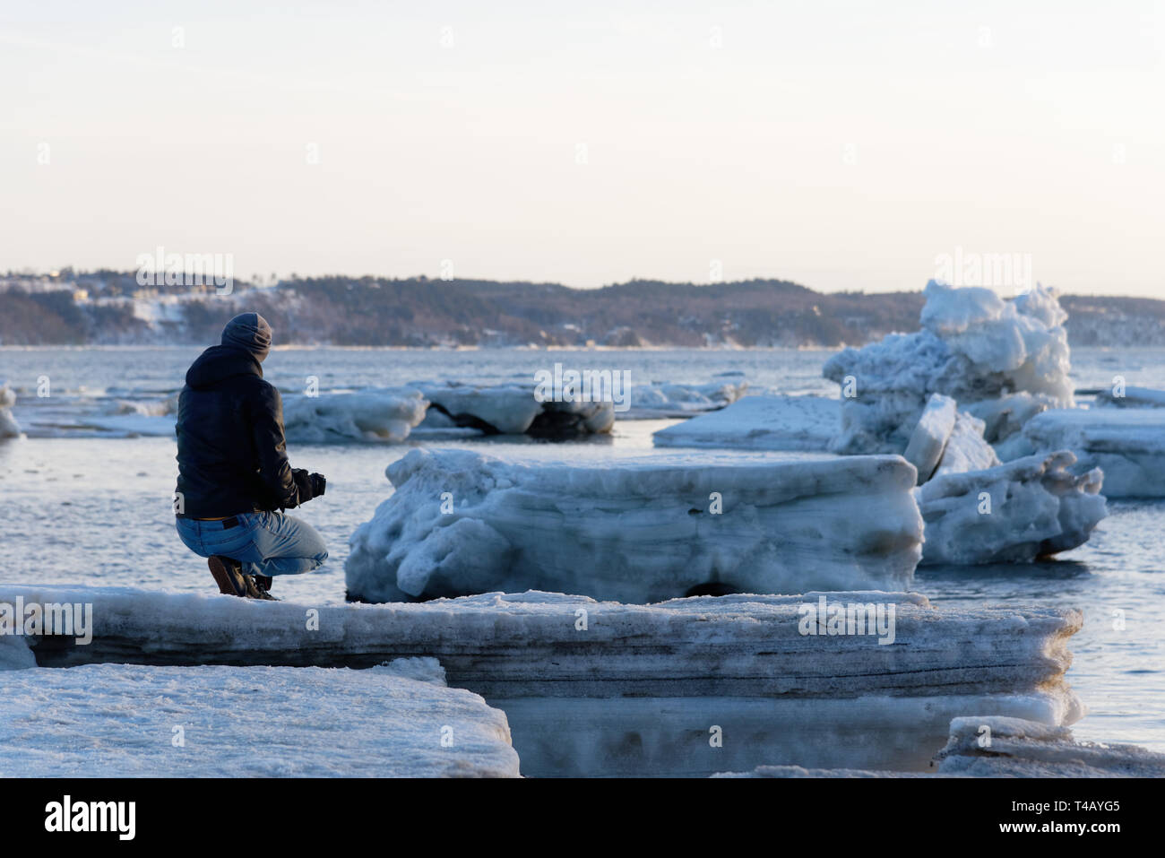 Un homme à genoux sur la banquise sur la rive sud du Saint-Laurent à Cap Rouge, Québec, Canada Banque D'Images