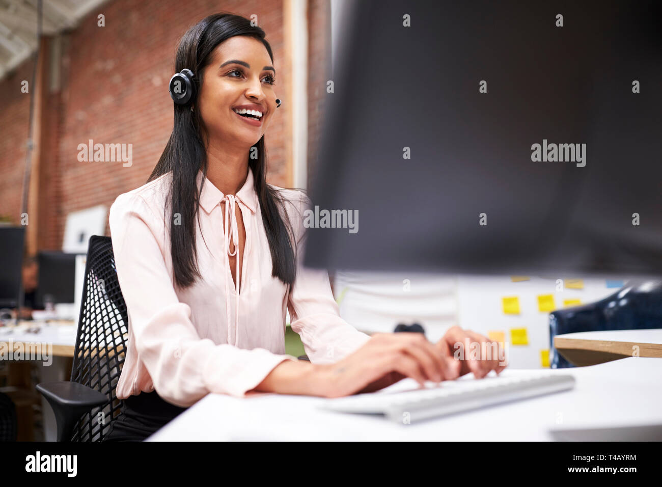 L'agent des services à la clientèle féminine travaillant au Bureau en Centre d'appel Banque D'Images