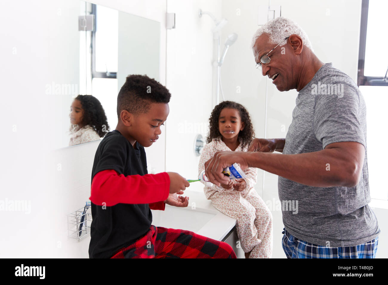 Grand-père dans la salle de bains Wearing Pajamas Aider les petits-enfants de se brosser les dents Banque D'Images