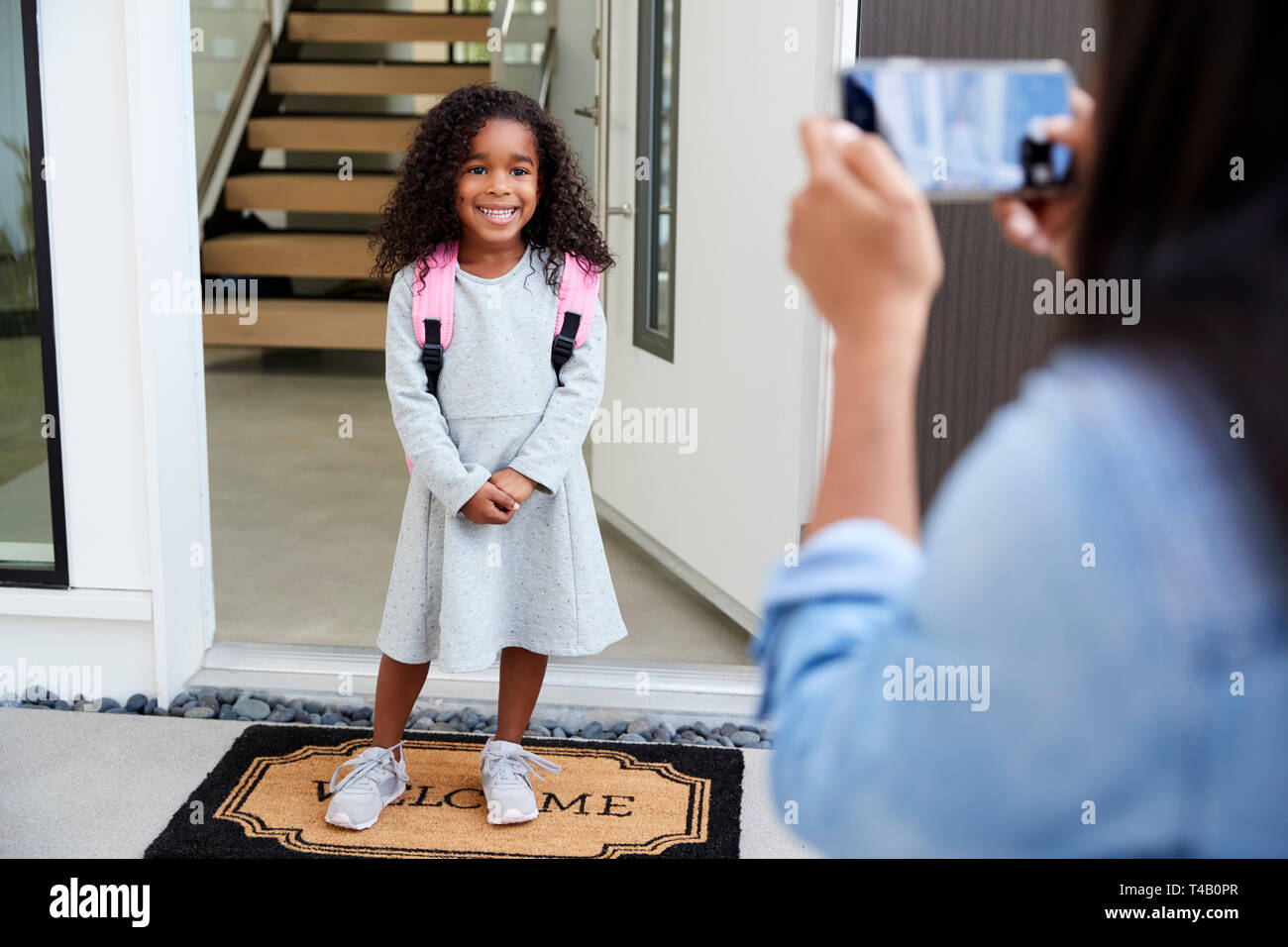 Mère de prendre Photo de fille avec téléphone cellulaire sur première journée de retour à l'école Banque D'Images