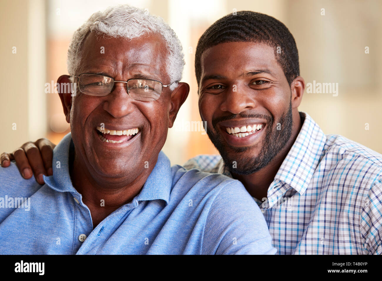 Portrait Of Smiling Senior Père câlins par fils adulte à la maison Banque D'Images
