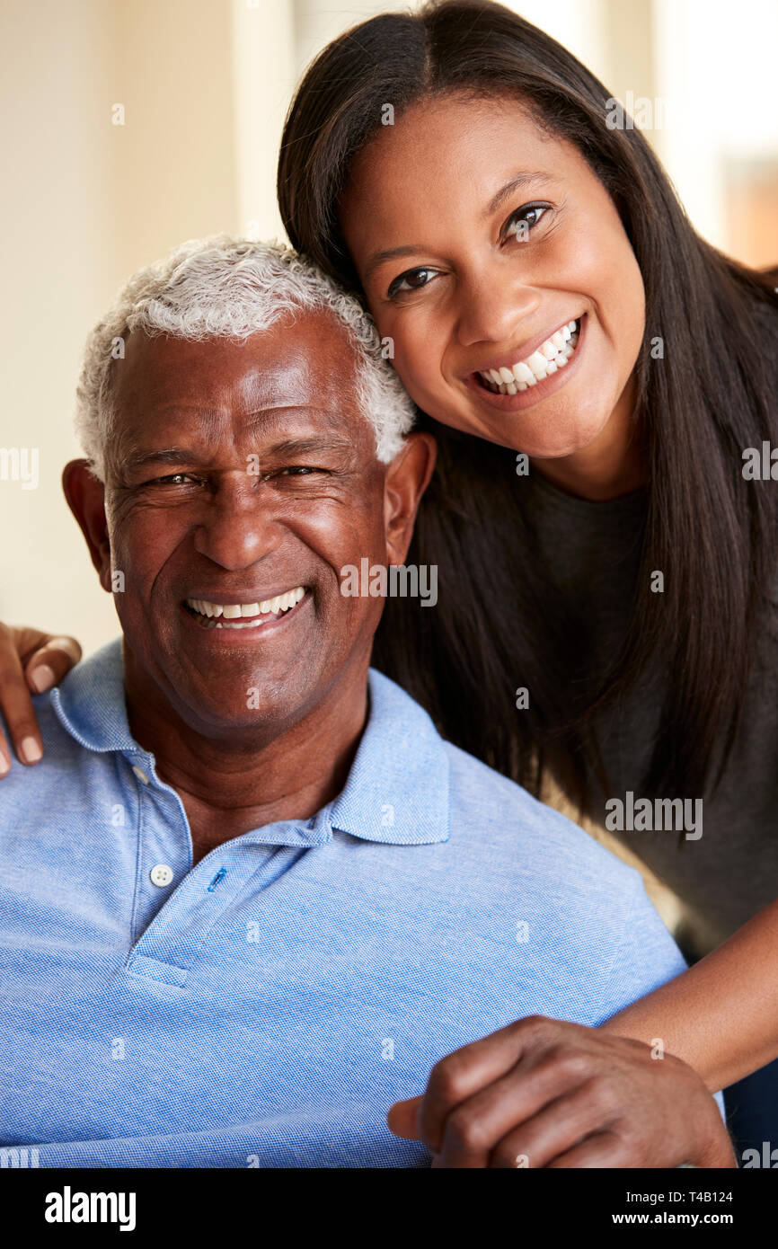 Portrait Of Smiling Senior Père câlins par sa fille adulte à la maison Banque D'Images