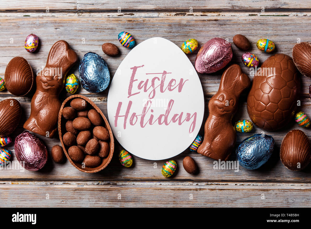 Les oeufs de pâques en chocolat et les lapins sur un fond de bois rustique Banque D'Images