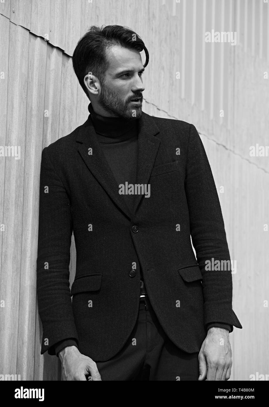 Barbe de mode style business beau mâle modèle avec look concentré grave posant dans des vêtements de style extérieur mur arrière-plan. Closeup portrait. B Banque D'Images