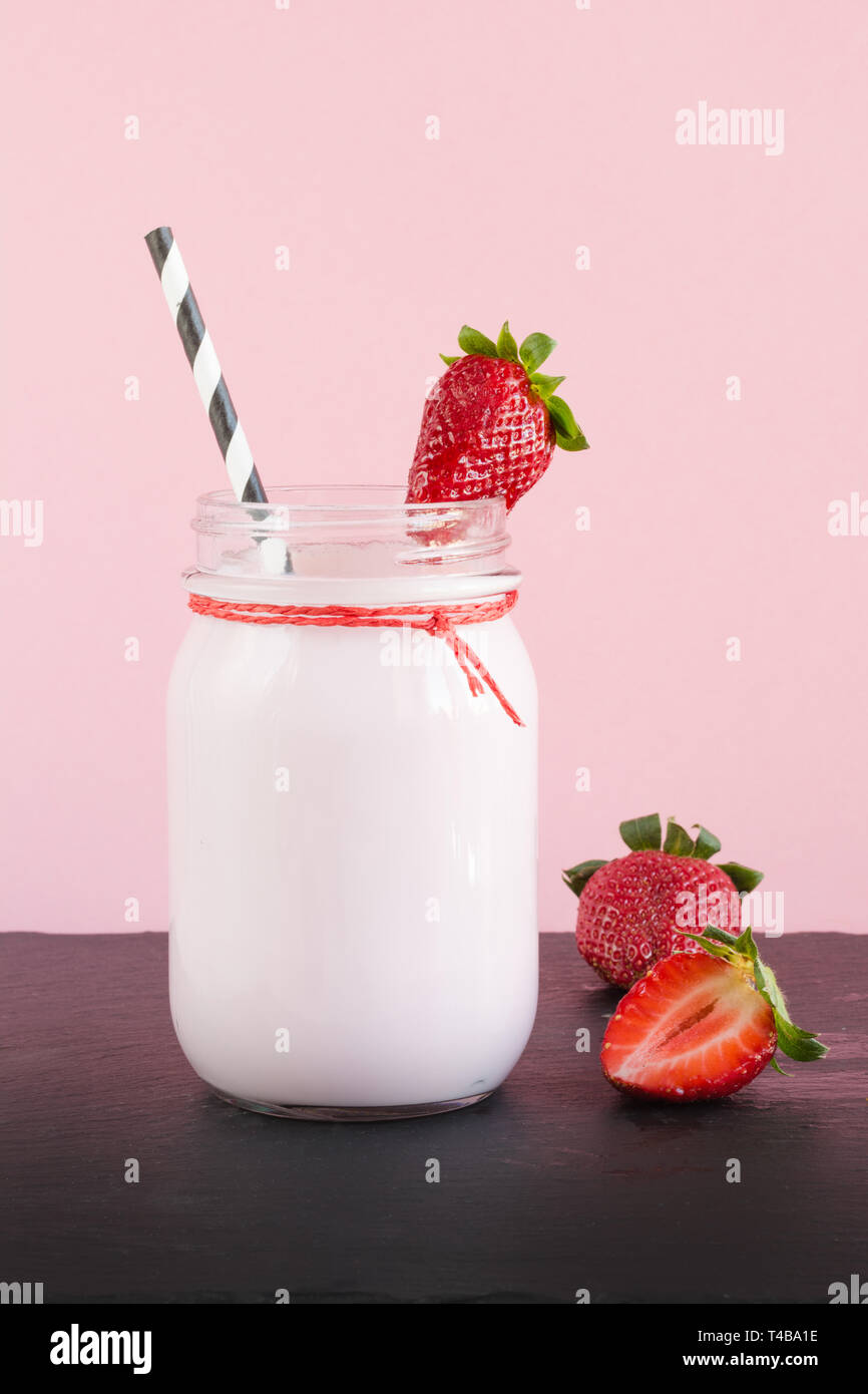 Lait frappé aux fraises avec berry en pot Mason sur rose. Close up. Boisson d'été. Banque D'Images Lait frappé aux fraises avec berry en pot Mason sur rose. Close up. Boisson d'été. Banque D'Images