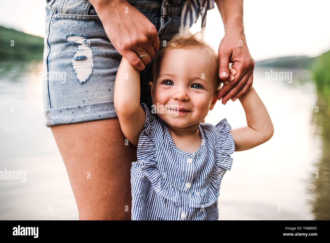 Un portrait de mère avec un enfant en fille à l'extérieur de la rivière en été. Banque D'Images