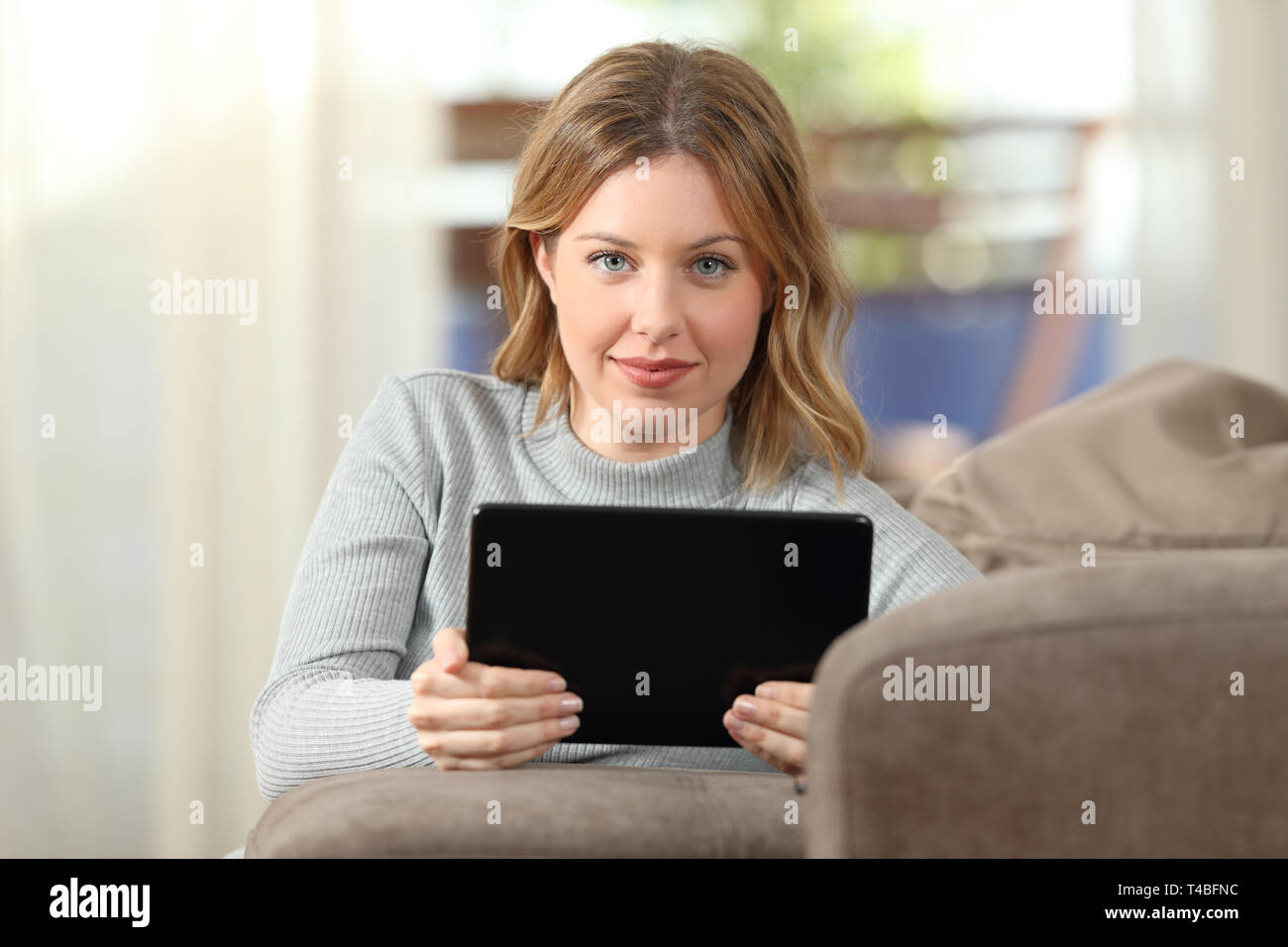 Vue avant portrait of a beauty woman looking at camera holding tablet Banque D'Images