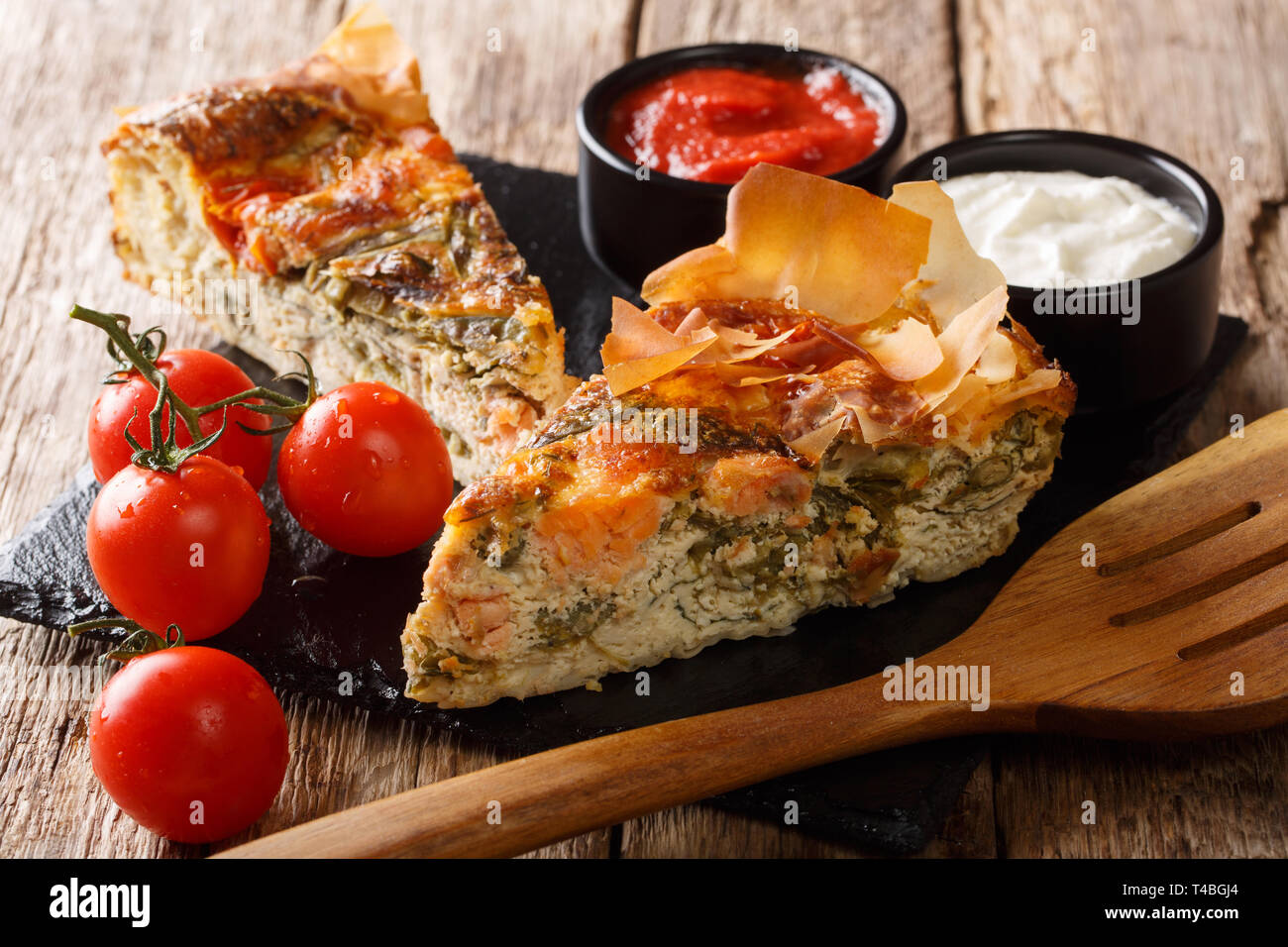 Tarte fraîchement cuits au four avec du saumon, tomates, fromage et herbes close-up sur la table horizontale. Banque D'Images