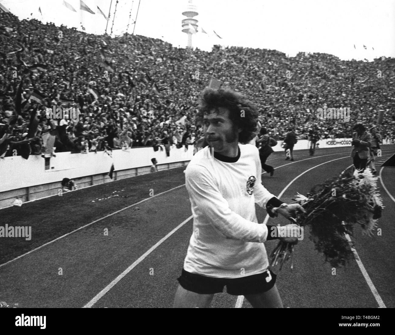 Le milieu de terrain allemand Paul Breitner, qui joue habituellement pour le Bayern de Munich, jubilant lance un bouquet de fleurs dans la foule. L'équipe nationale allemande remporte la finale de la Coupe du Monde contre les Pays-Bas le 7 juillet 1974 devant 80 000 spectateurs au Stade olympique de Munich par un score final de 2-1 et remporte le titre de Coupe du monde pour la deuxième fois. Dans le monde d'utilisation | Banque D'Images