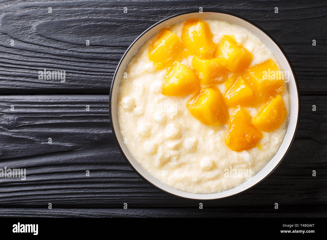 Pouding au tapioca sucré avec du lait de coco et mangue fraîche close-up dans un bol sur la table. Haut horizontale Vue de dessus Banque D'Images