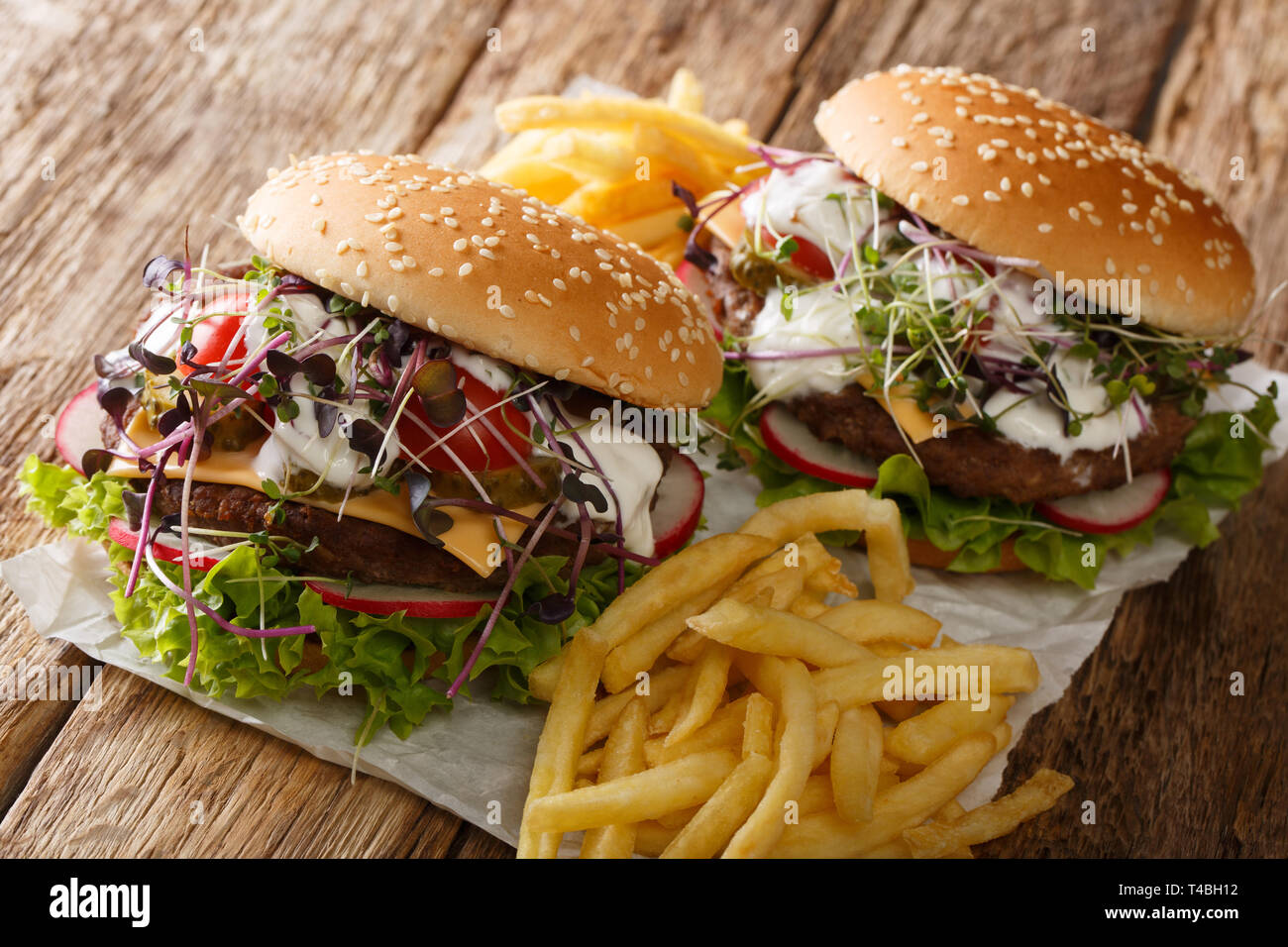 Les burgers de printemps avec des légumes frais, microgreen, fromage cheddar et sauce blanche, avec des frites sur la table horizontale. Banque D'Images