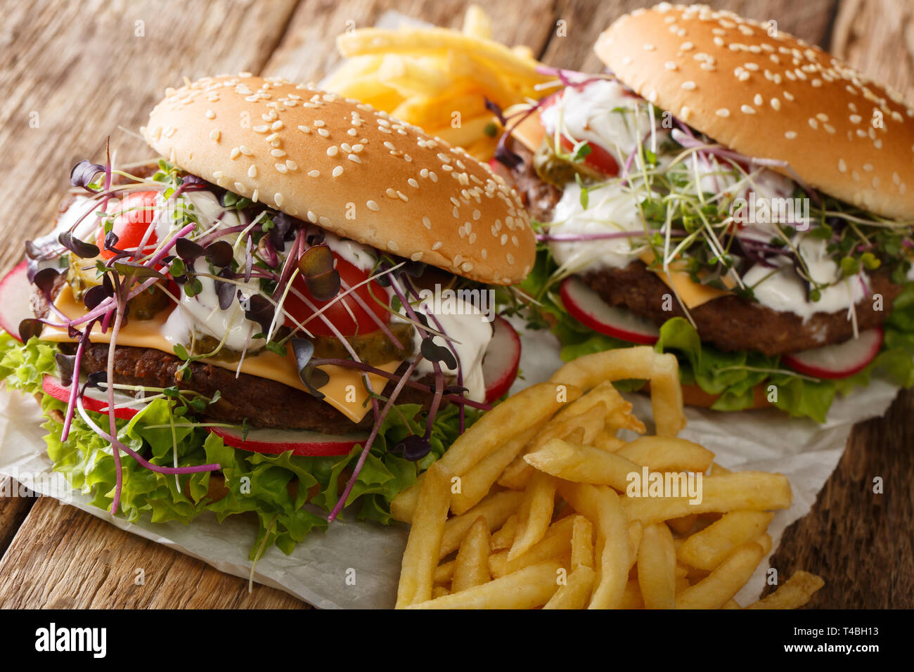 Des sandwichs hamburgers de légumes frais, microgreen, fromage cheddar et de yaourts servis avec frites close-up sur la table horizontale. Banque D'Images