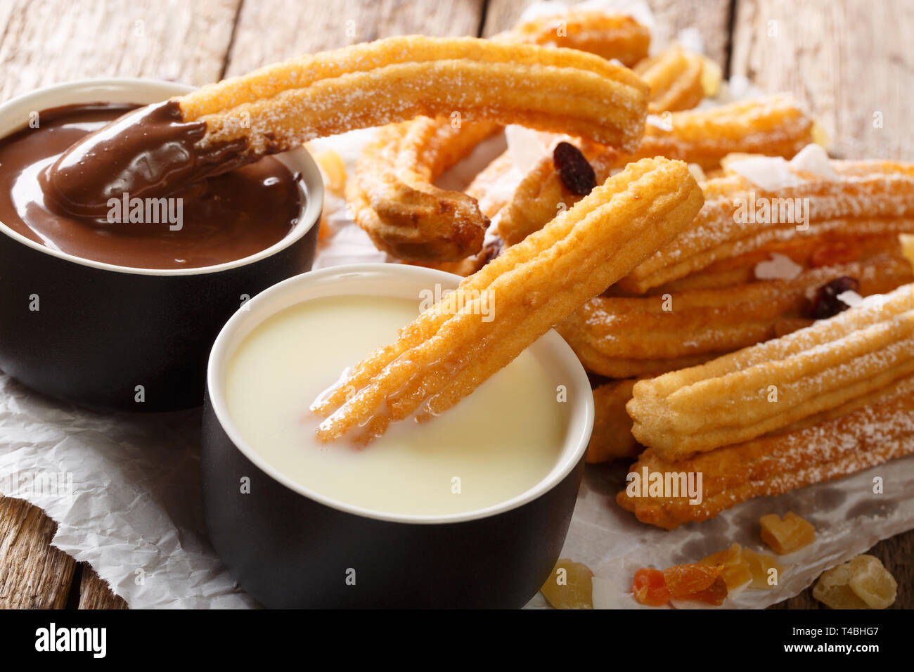 Dessert espagnol churros servi avec du chocolat chaud et de lait concentré sur la table horizontale. Banque D'Images