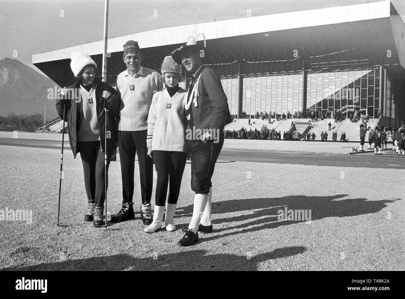 Trois membres de l'équipe autrichienne de la présenter aux Jeux Olympiques d'hiver de l'équipe officielle robes alors qu'une tyrolienne dans un costume traditionnel est debout à côté d'eux, 14 novembre 1963. Dans le monde d'utilisation | Banque D'Images