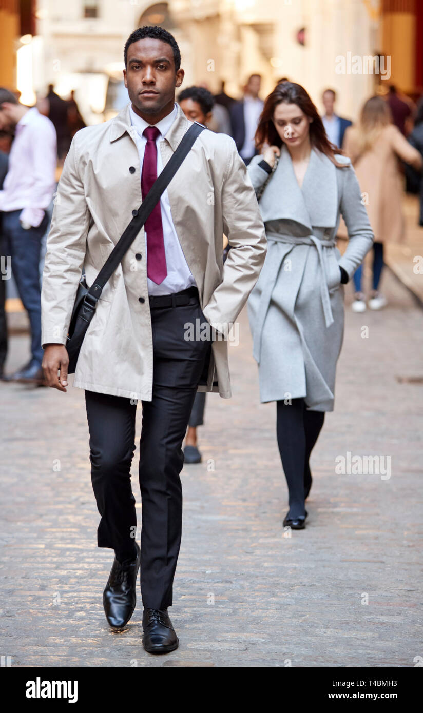 Black millénaire businessman walking dans une rue de la ville à la recherche d'appareil photo, pleine longueur Banque D'Images