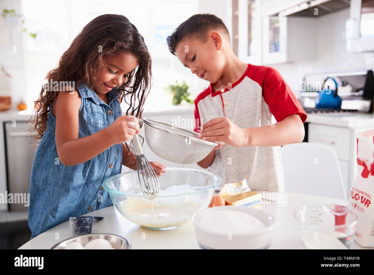 Frère et soeur de la préparation du mélange à gâteau ensemble à la table de cuisine, jusqu'à la taille Banque D'Images