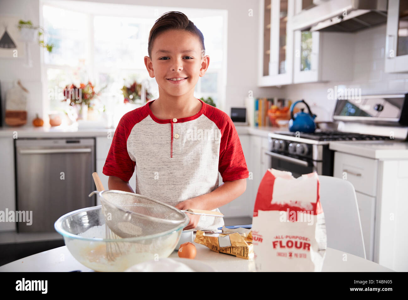 Pré-ado garçon fier de faire son propre mélange de gâteau dans la cuisine, smiling, portrait Banque D'Images