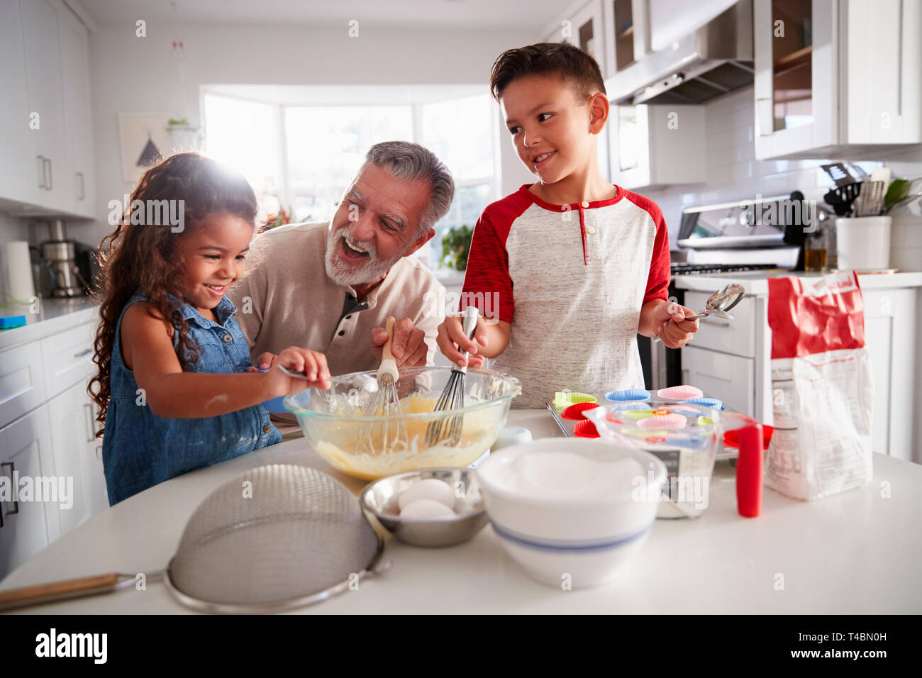 Frère et sœur debout à la table de cuisine faire un mélange à gâteau avec leur grand-père, Close up Banque D'Images