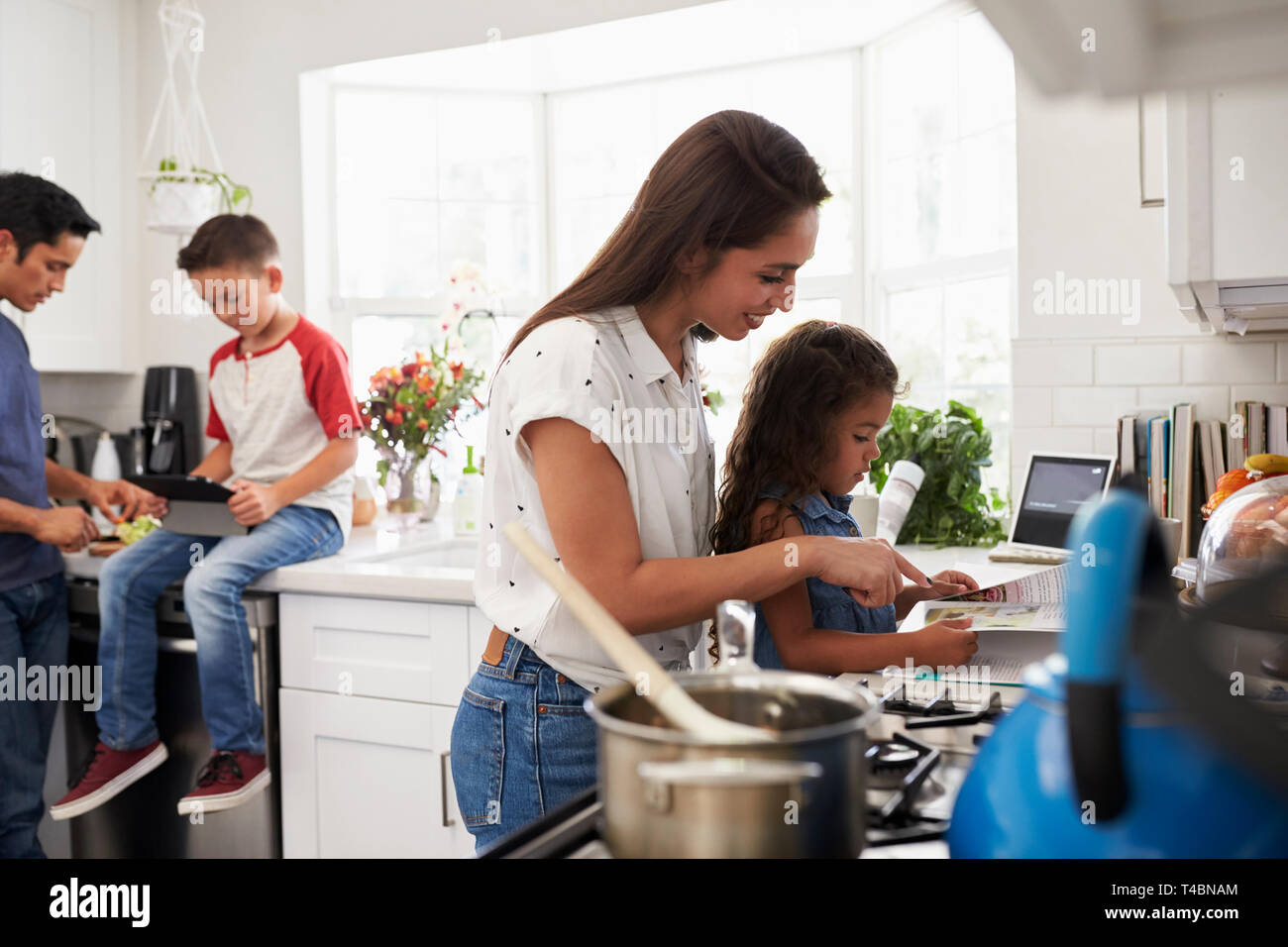 Mère et fille, la préparation de la nourriture dans la cuisine, père et fils pré-ado dans l'arrière-plan Banque D'Images