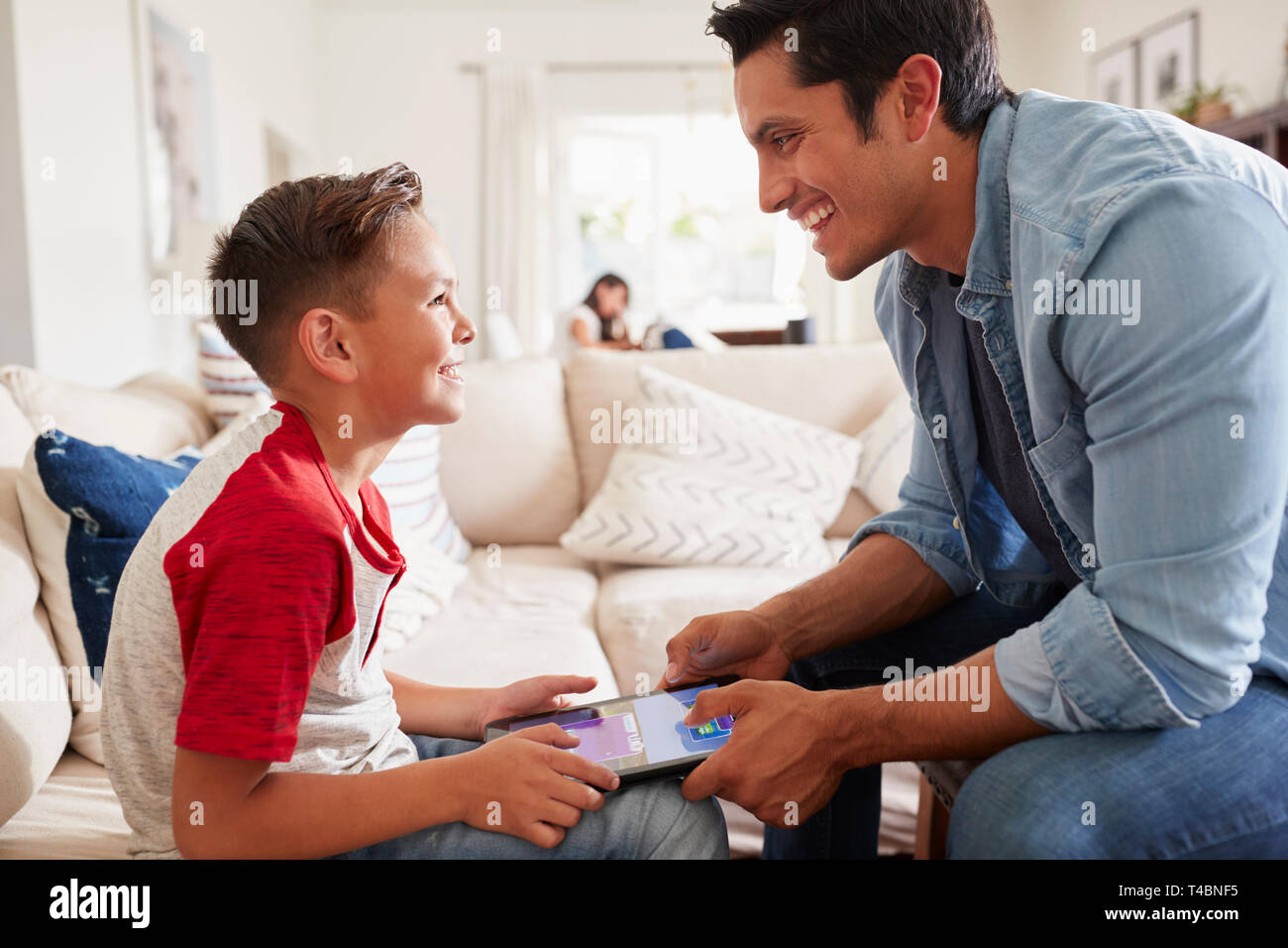 Pré-ado garçon et père de jouer à un jeu sur un ordinateur tablette dans le salon, Close up Banque D'Images