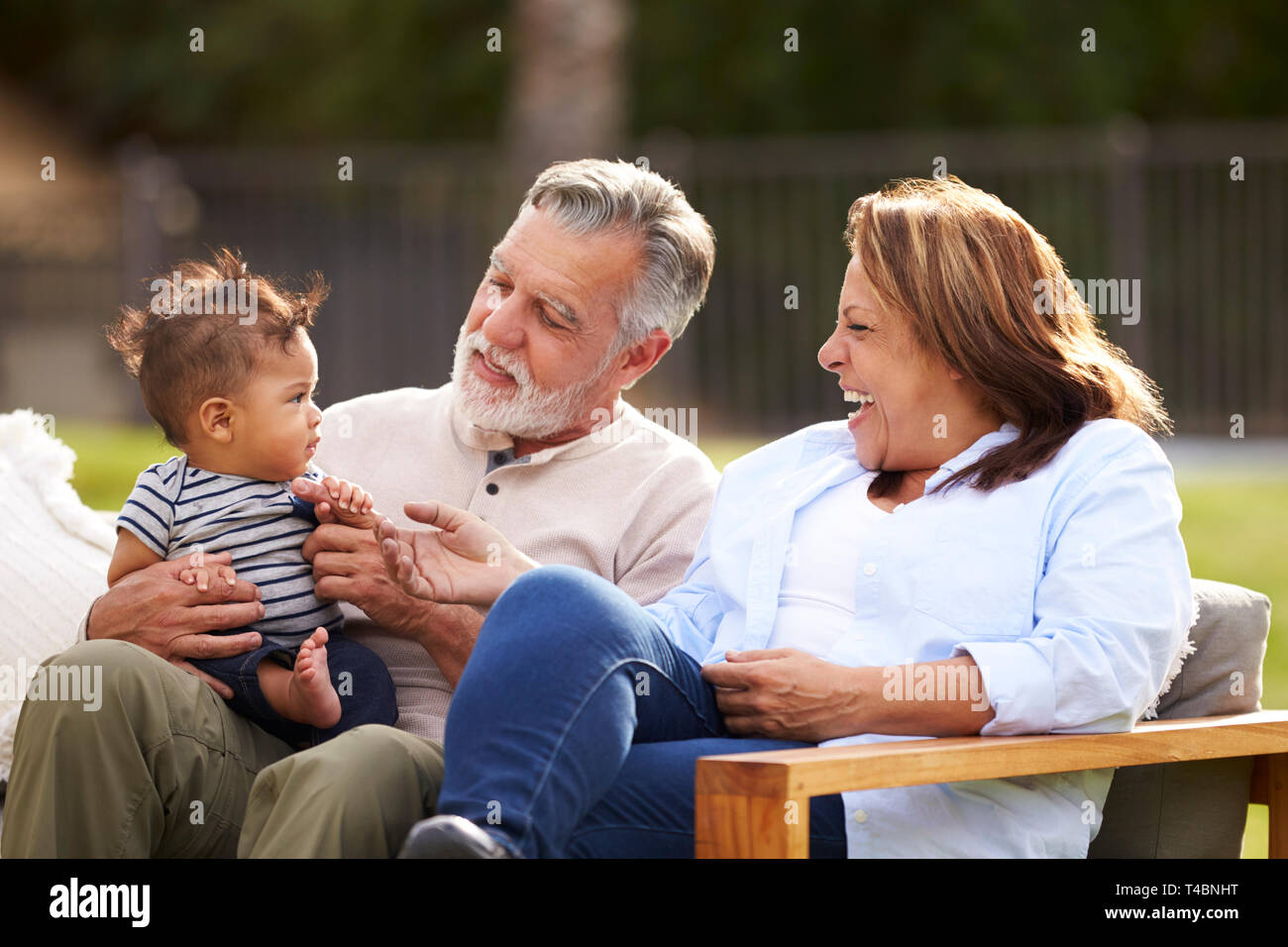Couple dans le jardin avec leur bébé petit-fils, en lui souriant, vue avant Banque D'Images