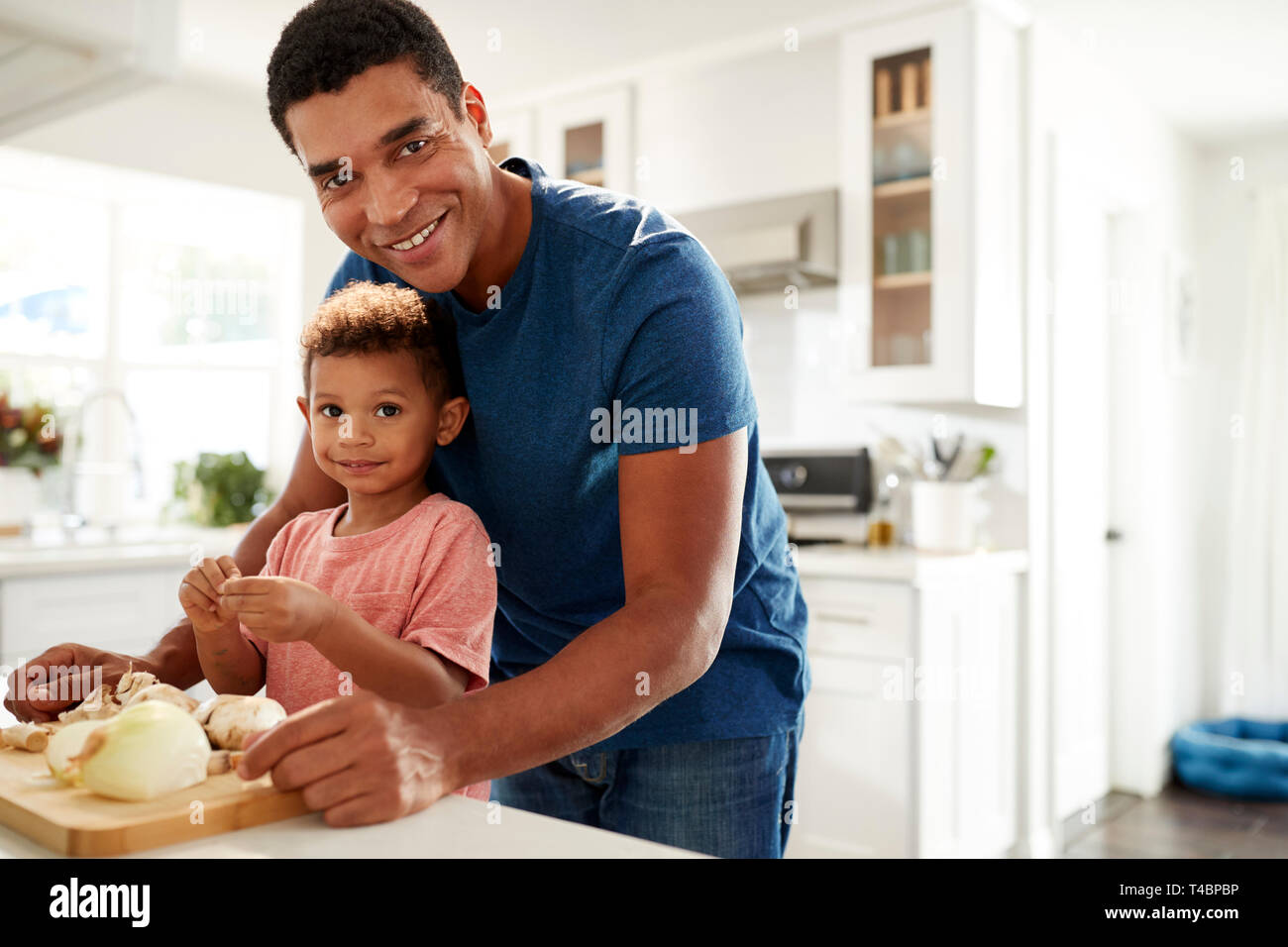 Homme debout à millénaire plan de cuisine la préparation des aliments avec son petit garçon à la recherche d'appareil photo, Close up, premier plan de discussion Banque D'Images