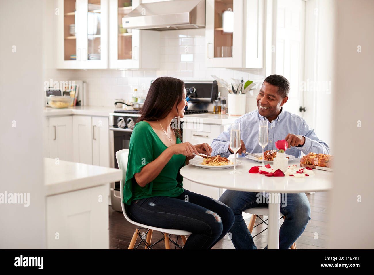 Middle aged hispanic couple manger un repas romantique ensemble dans leur cuisine, Close up Banque D'Images