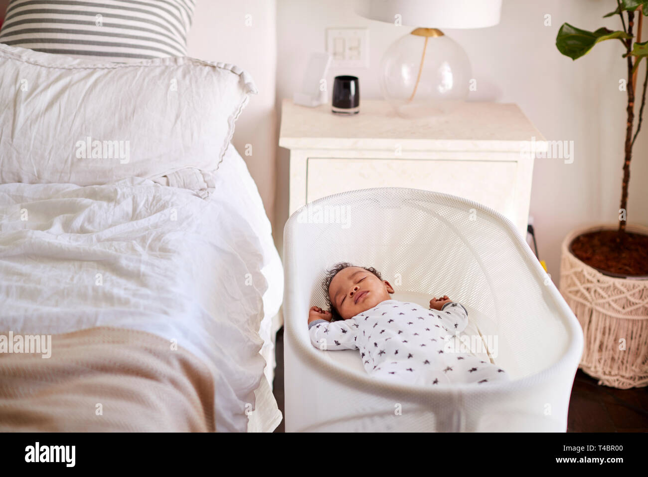 Trois mois bébé endormi dans son lit à côté du lit dans la chambre de sa mère Banque D'Images