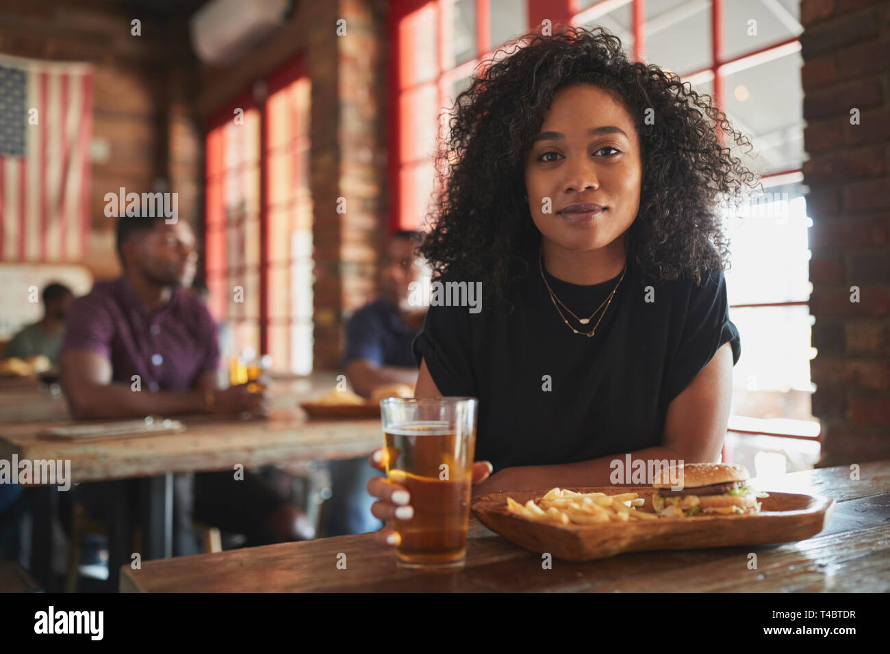 Portrait de femme au Sports Bar manger burger et frites Banque D'Images