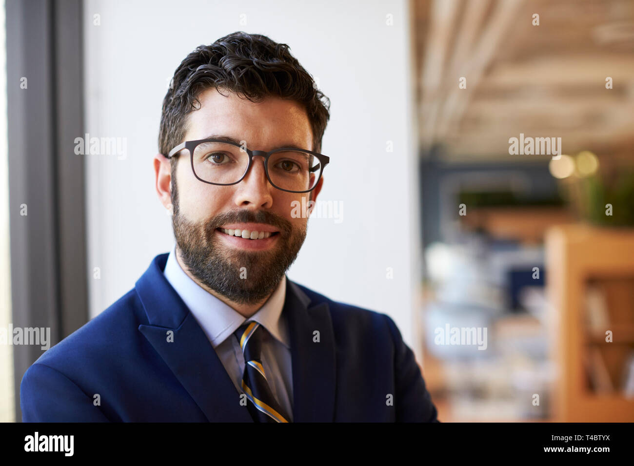Portrait Of Businessman in Modern Office Standing By Window Banque D'Images