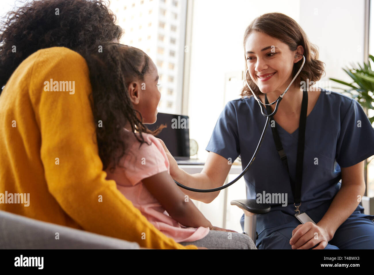 Pédiatre femelle portant des gommages corporels à l'écoute des jeunes filles à l'hôpital Chest with Stethoscope Office Banque D'Images