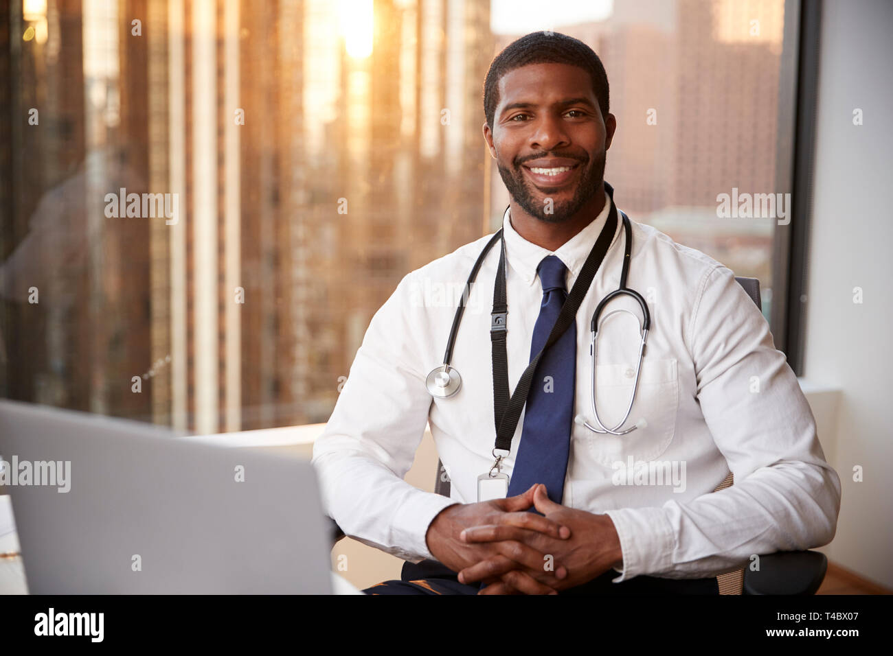 Portrait Of Smiling Male Doctor with Stethoscope in Hospital Office Banque D'Images