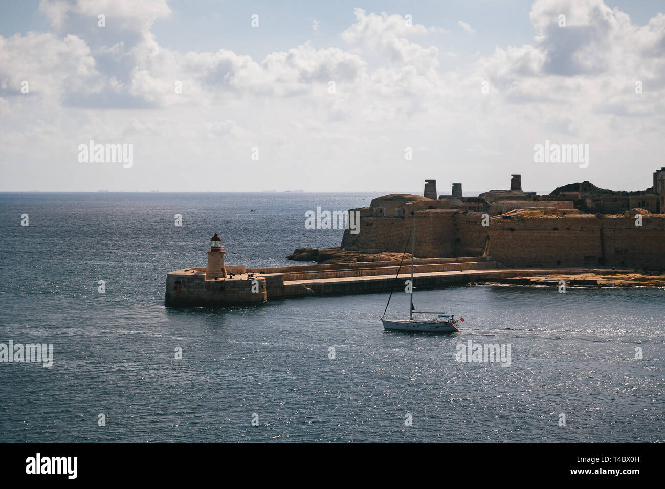 Vue sur le Grand Port et de la vieille ville médiévale d'Aiguilhe brise-lames est rouge avec phare et Fort Ricasoli vu de La Valette, Malte Banque D'Images
