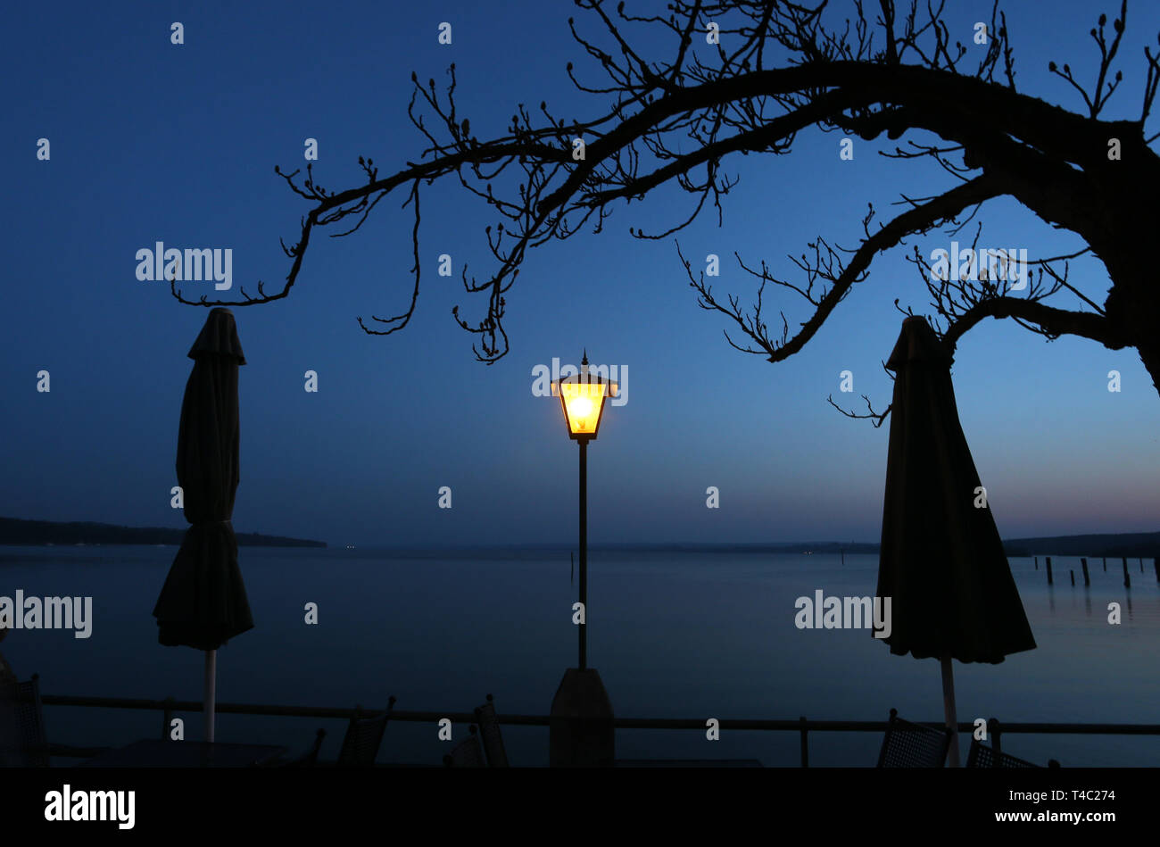 Manche, en Allemagne. Apr 15, 2019. Une lanterne est à l'heure bleue dans un jardin au bord de l'Ammersee entre deux parasols. Credit : Karl-Josef Opim/dpa/Alamy Live News Banque D'Images