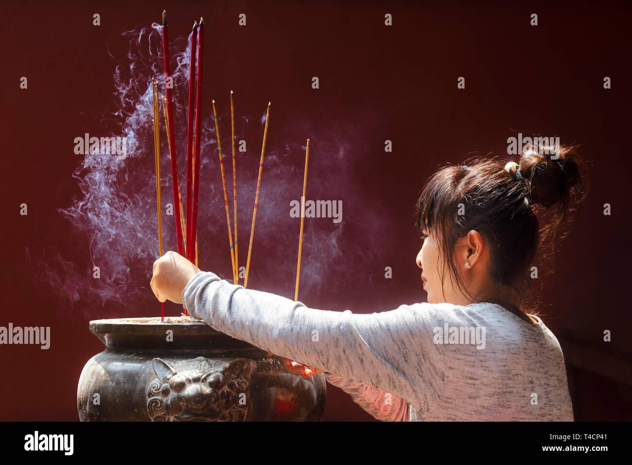 Jeune femme à la combustion d'encens sur le Nouvel An Chinois, complexe du temple Wat Phnom Daun Penh, Phnom Penh, Cambodge Banque D'Images
