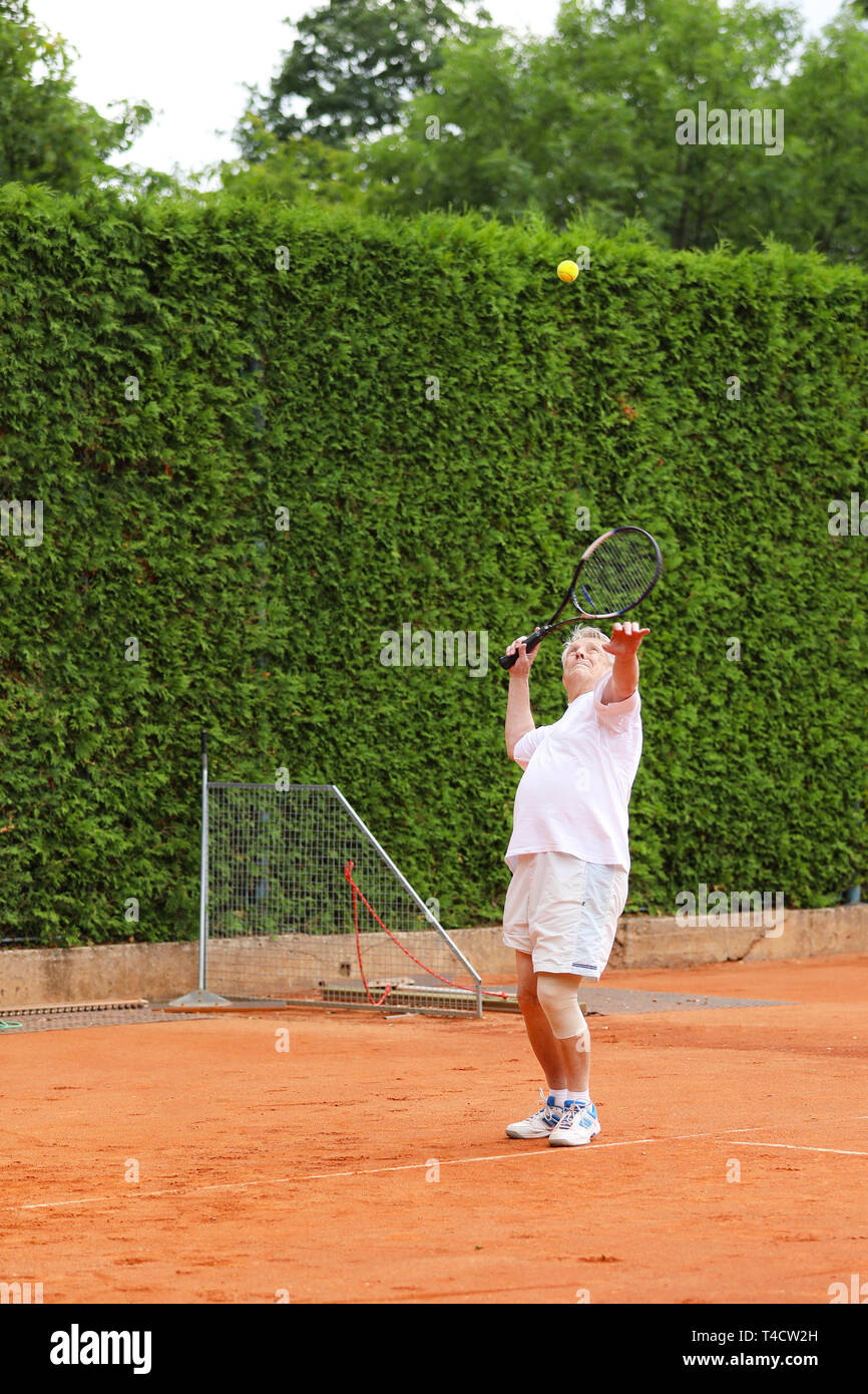 Pensionné actif moderne servant des balle de tennis Banque D'Images